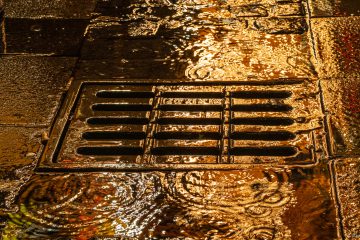 Die Lichter des Weihnachtsmarktes spiegeln sich im regennassen Pflaster